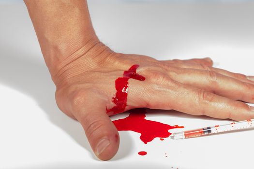 Subcutaneous medical injection concept with a small hypodermic syringe filled with a red liquid penetrating the skin and producing a flow of dripping blood in a close up view