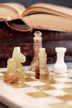 Set of chess pieces made from Onyx on board near books