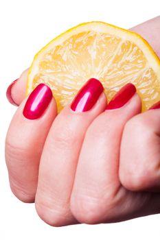 Hand with manicured nails painted a deep glossy red squeeze lemon on white background