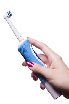 Hand with manicure holds single blue electric toothbrush against white background