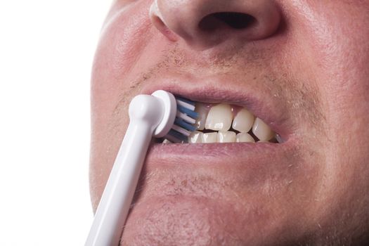 Close up of electric toothbrush with blue bristles and tube with paste bubbled at its opening on white background