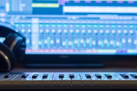Music production at night. With keyboard and headphones.