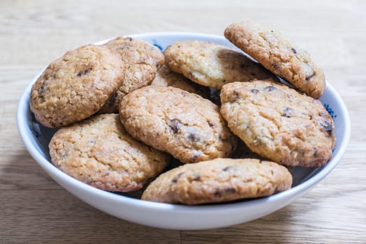 A white bowl full of home made chocolate chip cookies