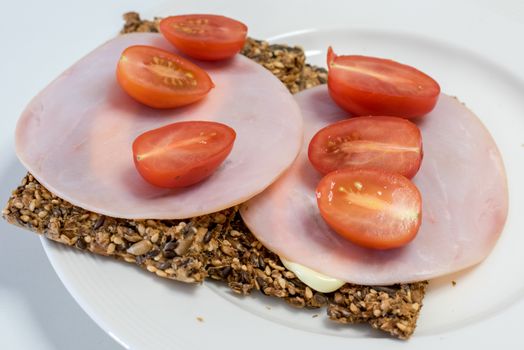 Crispy bread made from seeds, with tomatoes, ham and mayonnaise