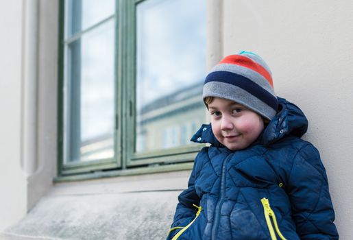 Young boy leaning agains concrete wall.