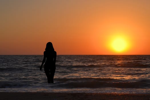 Silhouette of a girl in the water at sunrise