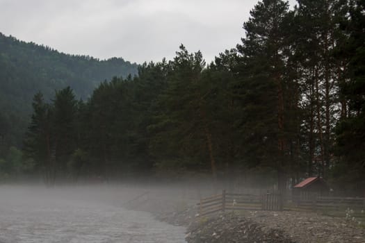 The fog is spread along the fast river early in the morning.