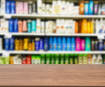 Wooden board empty table in front of blurred background. Perspective brown wood board over blurred colorful supermarket products on shelvest - mock up for display of product.