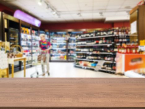 Wooden board empty table in front of blurred background. Perspective brown wood over blur in supermarket with unrecognizable customer. Mock up for display or montage of product.