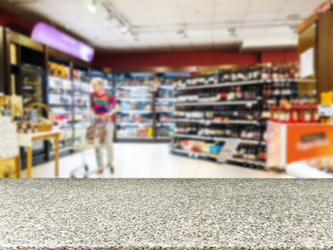 Marble board empty table in front of blurred background. Perspective marble table over blur in supermarket with unrecognizable customer. Mock up for display or montage of product.