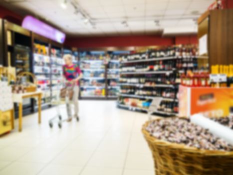 Abstract blurred supermarket aisle with colorful shelves and unrecognizable customers as background