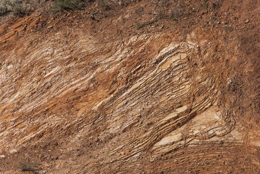 The reddish-brown rock called ribbon chert. This hard sedimentary stone originates from the Pacific deep-sea clay full of the microscopic shells, and is a type of a sedimentary rock.