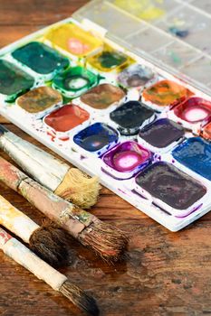 Set of watercolors and different brushes for painting on wood vintage palette