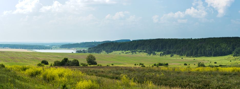 Wonderful summer panoramic view of fields with lake