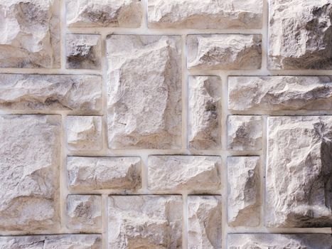 a wall from an artificial gray stone facade with rough fractured surfaces