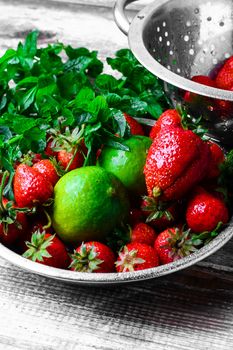 Dish with ripe large strawberries,lime and peppermint leaves