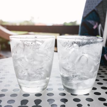 Glasses with ice cubes on black dot background table .