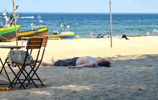 Sopot-Poland June-2016, Tired man lying down on sand in shadow spot on the beach at Baltic sea.