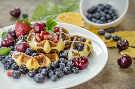 Homemade waffles with strawberry , blueberry and cherry on white plate
