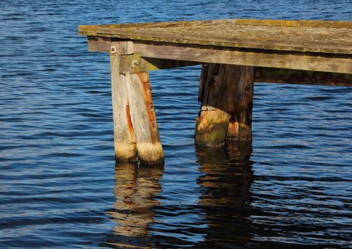 End of Old Wooden Pier with Dark Blue Water Reflection