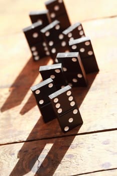 Black dominoes standing in a row on wooden background