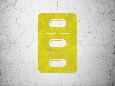 Medicine concept: Yellow Pills Blister on textured concrete wall background