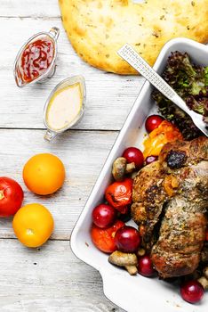 Twisted meatloaf with veal in plum sauce and vegetables in baking dish