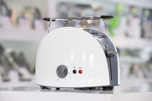 Single brand new white plastic shiny toaster at retail store shelf, defocused background