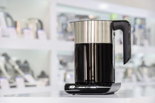 Single brand new premium electric kettle at retail store shelf, defocused background