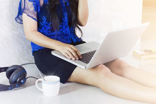 Lady sitting onthe floor surfing internet or working on notebook with cup of hot coffee in relax mood at home