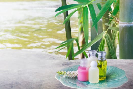 Mini set of bubble bath and shower gel liquid and frangipani flower on pebble rock and green nature relaxing spa  feeling with green bamboo tree background