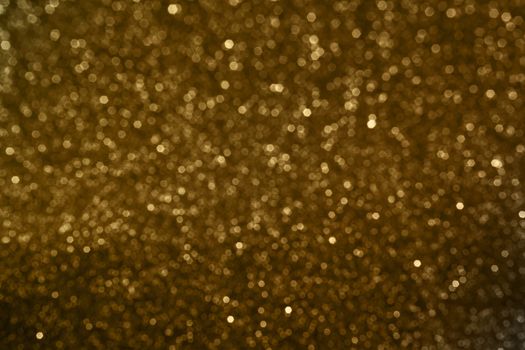 Small bokeh light sparkle shining on golden dark background