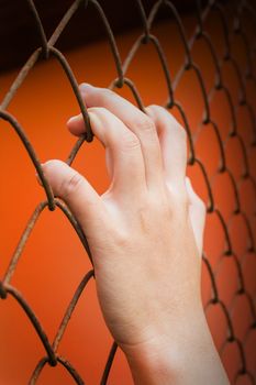 Women hand catching iron bar on orange background, imprison feeling