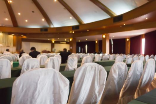 Blurred background of empty chairs with people in convention or meeting room