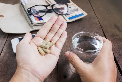 Herb medicine on hand and glass of water on work table