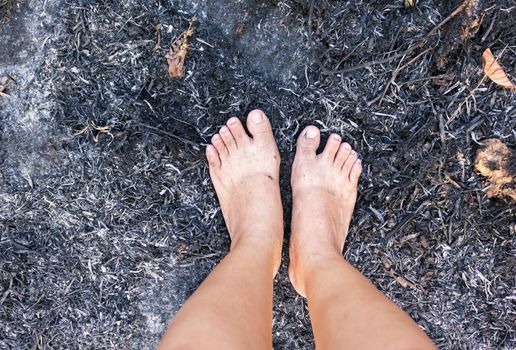 Barefoot on forest burnt cinders ground, concept world forest protect