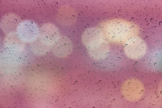 Water or rain drop on mirror glass plate window with bokeh abstract soft pink background