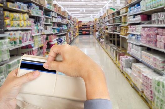 Isolated business women hands pull credit card out of wallet with shopping mall blurred background and copy space