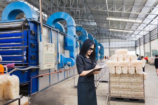 Businesswomen or entrepreneur investigate productivity or quantity of products with  factory blurred background