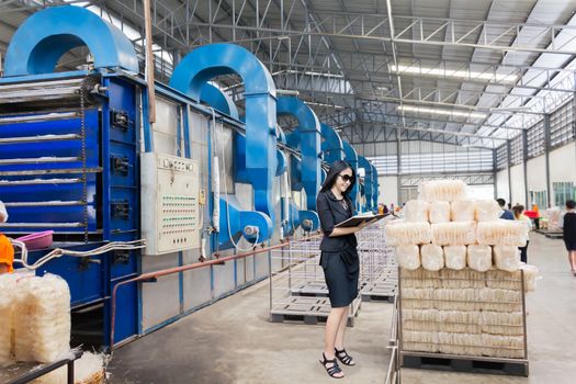 Businesswomen or entrepreneur investigate productivity or quantity of products with  factory blurred background