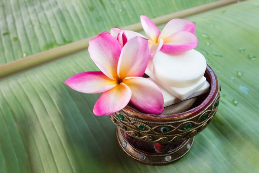 Mini set of shower bath soap with flowers frangipani on green banana leaf