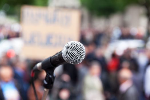 Microphone in focus against blurred crowd. Political rally.