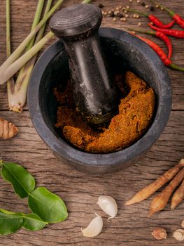 Assortment of Thai food Cooking ingredients and spice red curry paste ingredient of thai popular food on rustic wooden background. Spices ingredients chilli ,pepper, garlic,galanga and Kaffir lime leaves .
