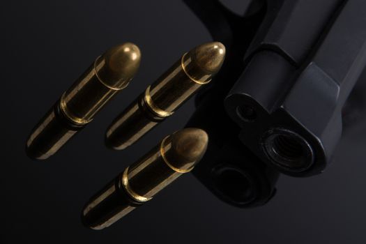 Gold bullets and gun on black background