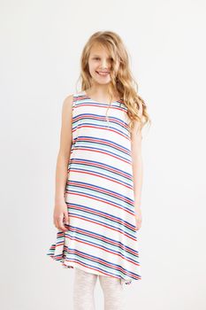 Lovely little girl in a striped dress in front of white background. Happy kids