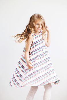 Lovely little girl in a striped dress against a white background. Happy kids