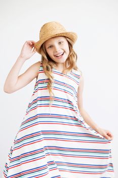 Lovely little girl with straw hat and striped dress against a white background. Happy kids