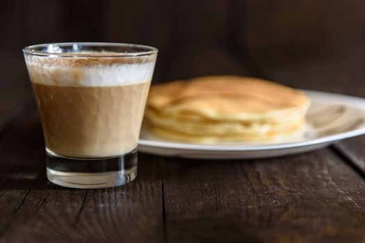 pancakes with chocolate topping and coffee cappuccino with corica on the table