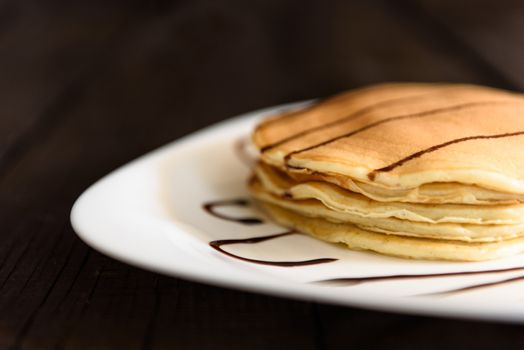 pancakes with chocolate topping and coffee cappuccino with corica on the table