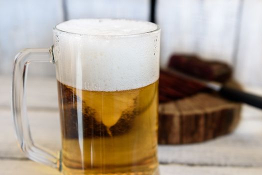 pastrami beer in a glass knife on a wooden table